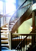 Natural Wood Stairs from upper level to basement level showingcurved handrailing.