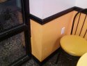 This is a picture of a damaged yellow corner wall by the window.